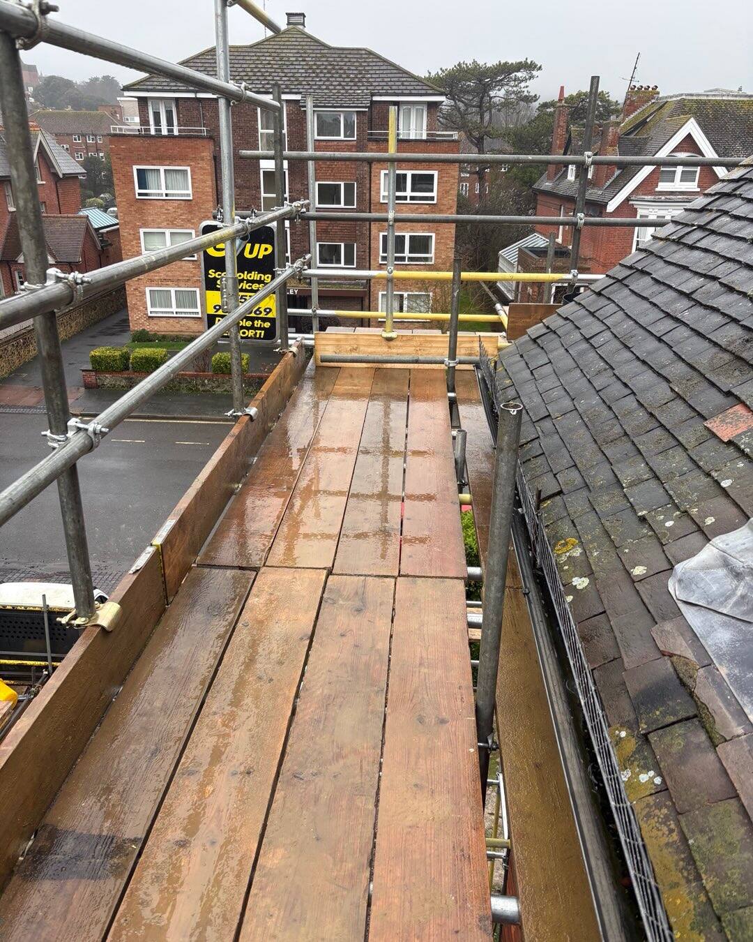 View along a wet scaffold deck overlooking Eastbourne red-brick apartment buildings